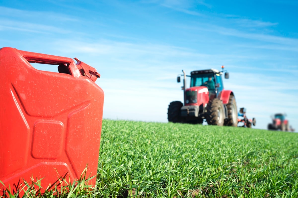 Gas can and tractor working in the field.